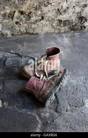 Una coppia di vecchi lavori di cuoio stivali sul pavimento del workshop Foto Stock