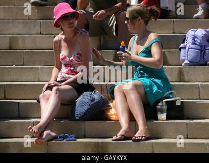 Il crema solare viene applicato mentre gli appassionati di tennis godono del caldo tempo durante il Wimbledon Championships 2008 all'All England Tennis Club di Wimbledon. Foto Stock