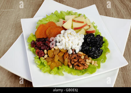 Vitamina insalata con dadi, mele, frutta secca e formaggio in foglie di lattuga Foto Stock