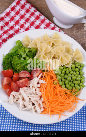 Insalata di broccoli, piselli, carote, pasta, pomodori ciliegini, le fette di pollo in salsa di latte Foto Stock