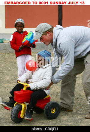 Il principe Harry spinge Mojabeng di quattro anni sul suo trattore durante una visita all'unità di consulenza del bambino del Lesotho in Maseru, Lesotho, Africa. Foto Stock