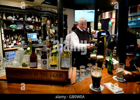 Il barista di colare una pinta di birra al vecchio pub Stand a Dublino Repubblica di Irlanda, Europa Foto Stock