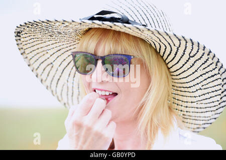 Bella donna rossetto indossando un floppy cappello per il sole all'esterno REGNO UNITO Foto Stock