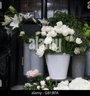 Tulipani bianchi, gigli e rose in una benna per la vendita Foto Stock