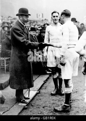 Il capitano dell'Università di Cambridge Geoffrey Conway (c) presenta il suo team HM King George V (l) prima della partita (L'ultima partita di varsity da giocare a Queen's) Foto Stock