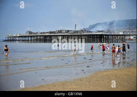 I vacanzieri sulla spiaggia accanto al Grand Pier a Weston-super-Mare dopo lo scoppio di un grande incendio. Foto Stock