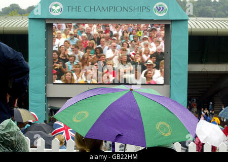 Tennis - Wimbledon 2003 - Semifinale - Justine Henin-Hardenne / Serena Williams. I fan guardano un replay del quarto finale femminile mentre la pioggia smette di giocare Foto Stock