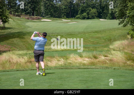 Vista da dietro il Golfer come egli oscilla Off tee da golf Foto Stock