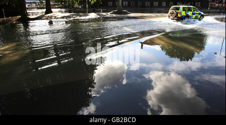 Una macchina della polizia attraversa una piscina d'acqua su una Kennington Road allagata fuori dalla stazione della metropolitana Oval, a sud di Londra, durante una fuga d'acqua. Foto Stock