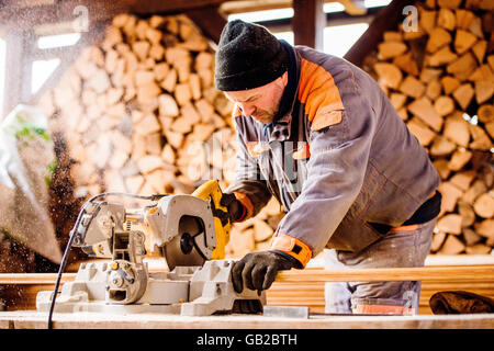 Carpenter funzionante. Uomo listone di taglio dalla sega circolare. Foto Stock