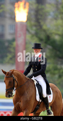 Sharon Hunt della Gran Bretagna cavalcando sulla città delle autocisterne, con la torcia olimpica che brucia sullo sfondo durante l'evento di dressage il secondo giorno delle Olimpiadi di Pechino del 2008 che si tengono al centro equestre Shatin, Hong Kong. Foto Stock