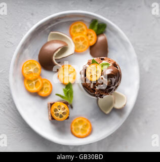 Cioccolatini e kumquat le fette su un piattino shot fom sopra, profondità di campo, il fuoco selettivo Foto Stock