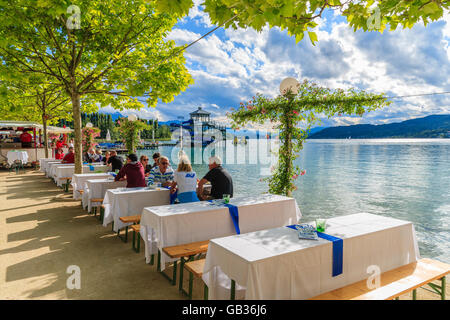 WORTHERSEE LAGO, Austria - giu 20, 2015: la gente seduta a tavoli lungo Worthersee lake shore durante l'estate del festival della birra. Foto Stock