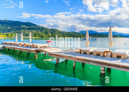 Sdraie sul molo in legno e la vista del bellissimo lago alpino Worthersee in estate, Austria Foto Stock