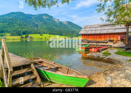 Lago Weissensee, Austria - Lug 6, 2015: Verde barche da pesca sulla riva del lago Weissensee in estate paesaggio della Carinzia terra, Au Foto Stock