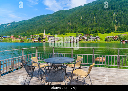 Le sedie intorno al tavolo sulla terrazza con vista del lago Weissensee in estate, Austria Foto Stock