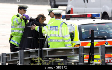 L'attivista Geoffrey Hibbert, che si ritiene sia legato alla Giustizia dei Padri 4, vestito come Batman, essendo scortato via da ufficiali di polizia dopo aver salito un portale sulla M25 vicino all'Aeroporto di Heathrow, Londra. Foto Stock