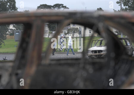 Una visione generale delle auto bruciate nella tenuta Tullygally a Craigavon, dopo che la polizia è stata pelata da bombe a benzina e altri missili. Foto Stock