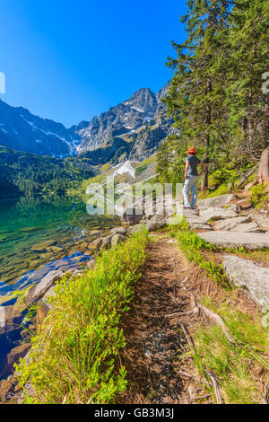 Giovane donna passeggiate turistiche sul percorso lungo il bel verde acqua Morskie Oko lago e monti Tatra, Polonia Foto Stock