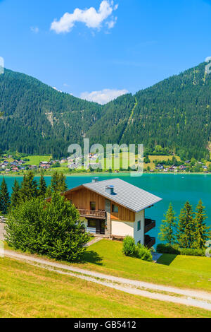 Tipica casa alpina sulla riva del bellissimo lago Weissensee in estate il paesaggio di montagna delle Alpi, Austria Foto Stock