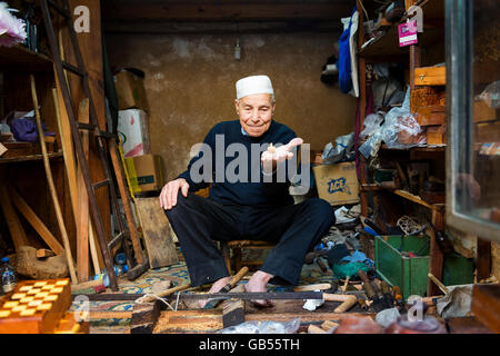 Fez, in Marocco - 11 Aprile 2016: Un artigiano che mostra una filatura top nel suo negozio nella Medina di Fez. Foto Stock