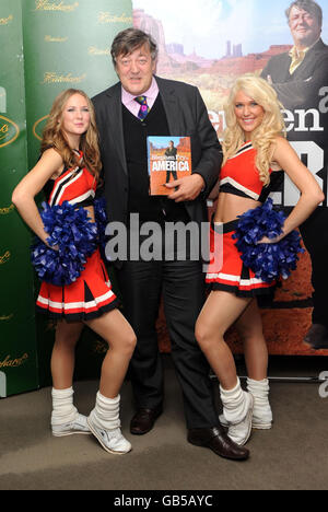 Stephen Fry firma copie del suo ultimo libro 'Stephen Fry in America' e posa con cheerleaders a Hatchards a Piccadilly, nel centro di Londra. Foto Stock