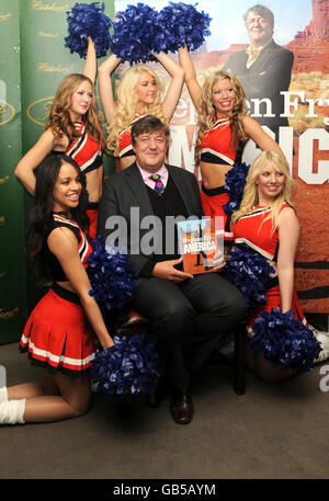 Stephen Fry firma copie del suo ultimo libro 'Stephen Fry in America' e posa con cheerleaders a Hatchards a Piccadilly, nel centro di Londra. Foto Stock