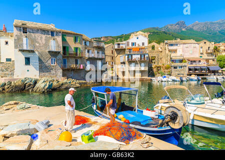 ERBALUNGA PORTA, CORSICA - Lug 4, 2015: pescatore reti di pulizia nel piccolo porto di Erbalunga. Questo piccolo villaggio di pescatori è Foto Stock