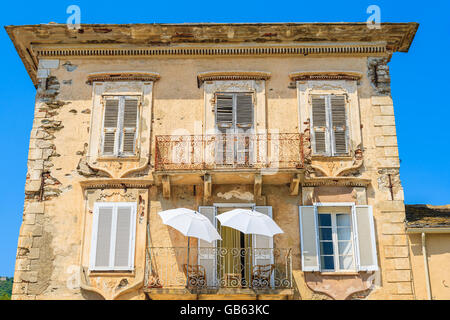 Due bianchi ombrelloni sul balcone di una tipica vecchia casa nella città di Erbalunga, Corsica, Francia Foto Stock