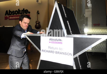 Il giorno in cui Absolute radio (ex Virgin radio) lancia, guardia di sicurezza della stazione Doug, ruota fuori il famigerato logo Virgin radio per essere inviato di nuovo a Virgin's Richard Branson, in One Golden Square, nel centro di Londra. Foto Stock