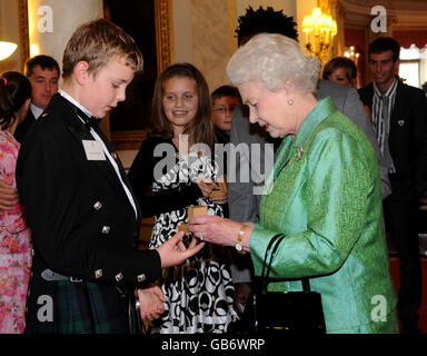 La Regina Elisabetta II della Gran Bretagna presenta un badge Gold Blue Peter a Connor Newlands, 12 anni, dalla Scozia, che salvò sua sorella Gemma dall'annegamento, durante un ricevimento che segnò il 50° anniversario del programma televisivo per bambini della BBC a Buckingham Palace, Londra. Foto Stock