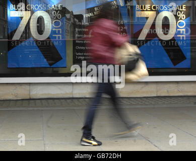 Uno shopping passa accanto a un cartello con lo sconto del 70% su Oxford Street a Londra. Foto Stock