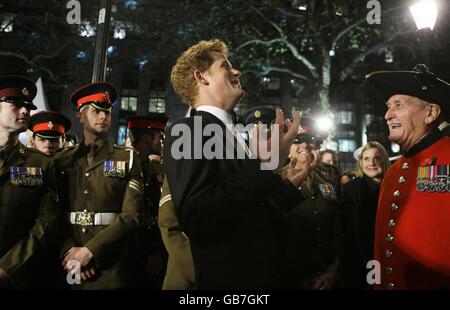 Il principe britannico Harry, centro, scherza con il pensionato Chelsea Stan Pepper, destra, mentre incontra il personale di servizio militare al suo arrivo per la prima mondiale del film di James Bond 'Quantum of Solace' ad un cinema a Londra. Foto Stock