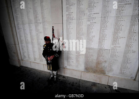 Un Piper suona un lamento davanti ai nomi di migliaia di soldati britannici e del Commonwealth che sono stati uccisi nella Grande Guerra dopo un servizio di memoria alla porta di Menin a Ypres, in Belgio, per celebrare il 90° anniversario della fine della Grande Guerra. Foto Stock