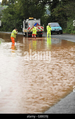 Gli addetti alla manutenzione delle autostrade lavorano per scolare il drenaggio sulla B3181 a Westcott, Devon, dopo una pesante pioggia notturna, hanno chiuso la strada e causato problemi di viaggio nella regione. Foto Stock