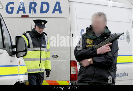 I REDATTORI SI PREGANO DI NOTARE I VOLTI OSCURATI DALL'ASSOCIAZIONE STAMPA SU RICHIESTA DELLA POLIZIA. Arbed Gardai sicuro Castletown Bere Pier in Co. Cork in attesa dell'arrivo dello yacht di lusso 'Dances with Waves' che è stato sequestrato al largo della costa occidentale dell'Irlanda, ieri portando un enorme raggio di cocaina. Foto Stock