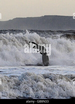 PRODOTTO ALTERNATIVO. Un surfista ama i mari pesanti di Scarborough, nello Yorkshire del Nord, mentre il freddo e la neve si prevedono che colpiscano alcune parti del Regno Unito questo fine settimana. Foto Stock