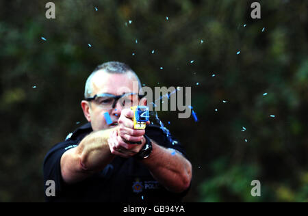 Un taser carica elettrica Paralizzatore elettrico essendo trattenuto in un  poliziotto la mano e volti Foto stock - Alamy