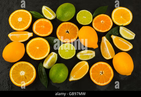 Lime, limone, arancio e mandarino su sfondo nero. Il cibo fresco. Frutti maturi. Gli agrumi. Cibo vegetariano. Frutta Mista. Freschi Foto Stock