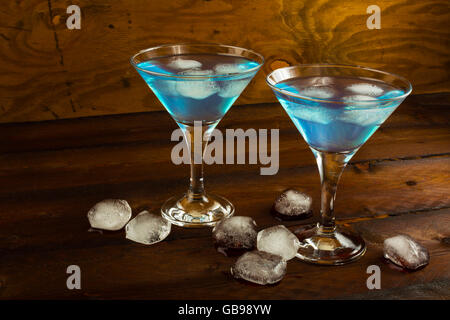 Due bicchieri di cocktail blu sul legno scuro dello sfondo. Il Blue Martini. La Blue Hawaiian cocktail. Foto Stock