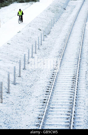 Un ciclista percorre un sentiero innevato nel North Tyneside, vicino a Newcastle, oggi, mentre un fronte artico ha colpito la costa orientale. Foto Stock