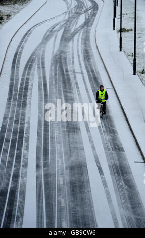 Un ciclista fa il suo senso lungo una strada coperta di neve in Tyneside del nord vicino Newcastle oggi mentre un fronte artico di tempo ha colpito la costa orientale. Foto Stock