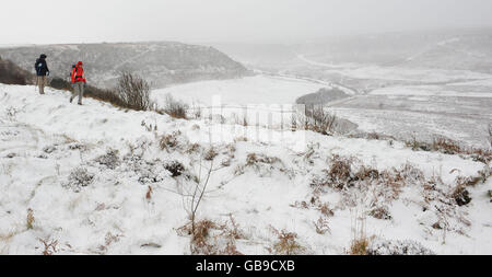 Camminatori nella neve al Hole-of-Horcum nel North Yorkshire Moors National Park come un fronte meteo artico colpisce il Regno Unito. Foto Stock