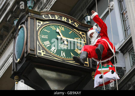 Santa scende oltre il famoso Clery's Clock su o'Connell Street, Dublino, per celebrare l'apertura della Grotta di Santa. Foto Stock