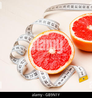 Concetto di dieta. Closeup pompelmo frutta con nastro di misurazione sul tavolo Foto Stock