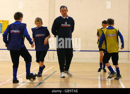 Il manager scozzese George Burley (centro), in collaborazione con i sostenitori della National Team Nationwide, si occupa di una sessione di coaching per giovani calciatori con sede alla Scottish fa Football Academy alla Graeme High School di Falkirk. Foto Stock