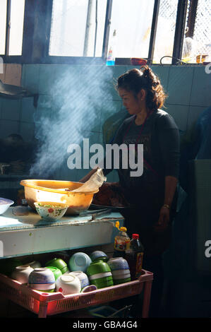 Lo Chef lavora al ristorante del riso, ella broit carne per com tam pasto, questo è specifico del cibo vietnamita di Dalat Foto Stock