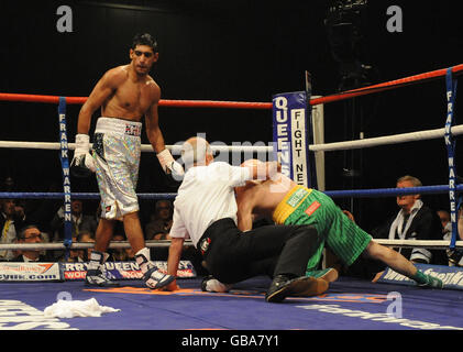 L'arbitro Mickie Vann si tuffa per salvare Irishman Oisin Fagan (a destra) nel secondo turno dopo essere stato battuto da Amir Khan (a sinistra) in Gran Bretagna nel leggero bout all'Excel Arena di Londra. Foto Stock