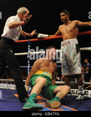 L'arbitro Mickie Vann fa un passo avanti per salvare Irishman Oisin Fagan (piano) nel secondo turno dopo essere stato battuto da Amir Khan (a destra) in Gran Bretagna nel bout leggero all'Excel Arena, Londra. Foto Stock