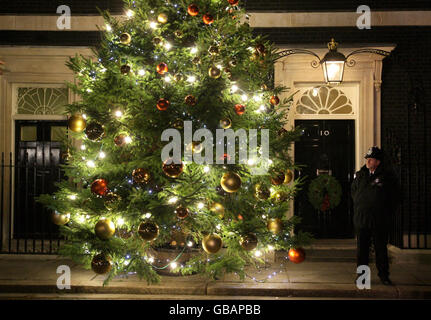 Un ufficiale di polizia si trova fuori 10 Downing Street a Londra, dopo l'accensione ufficiale delle luci dell'albero di Natale. Foto Stock